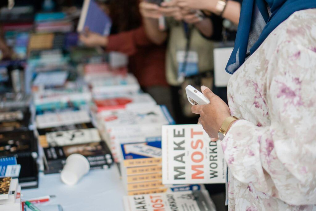 Close-up of various books on display at a book fair with attendees browsing.